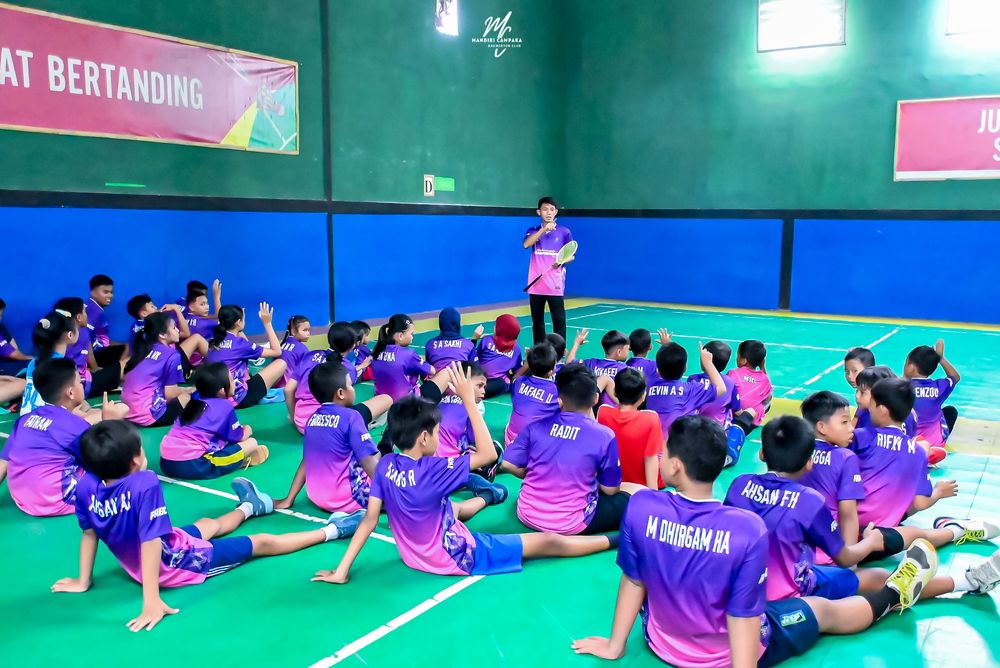 Atlet duduk mendengarkan pengarahan pelatih sebelum latihan