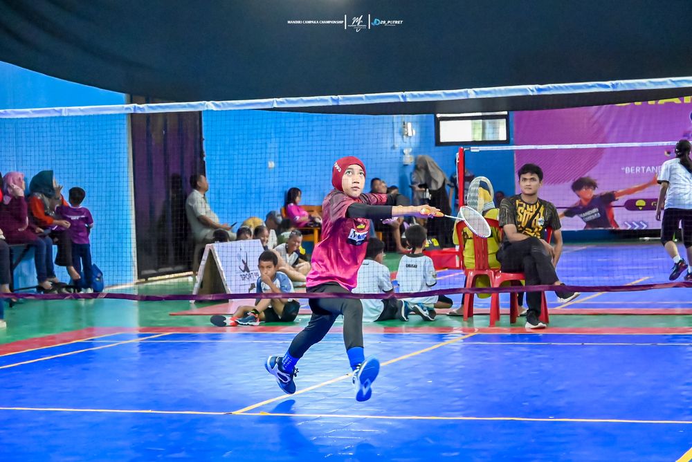 Atlet putri berhijab melakukan lunge di depan net