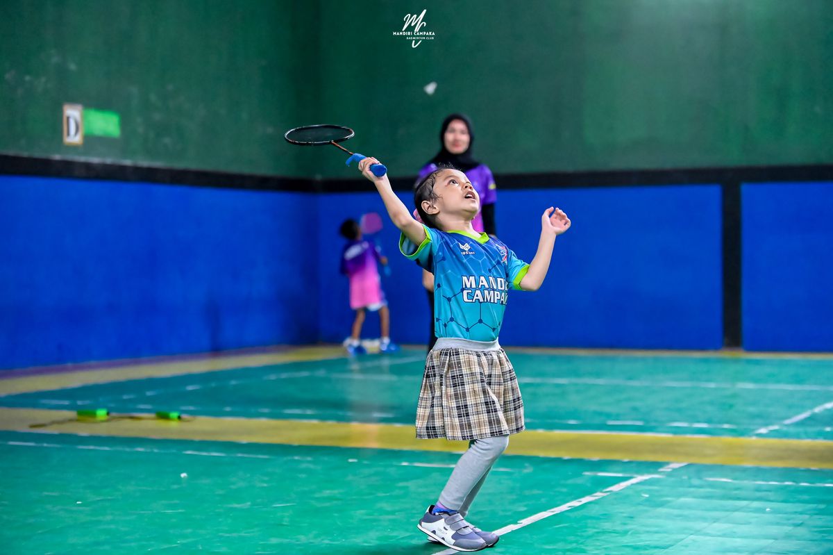 Anak kecil merentangkan tangan setelah memukul kok